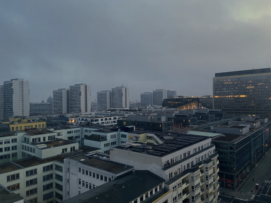 Berlin looking north-east across Mitte from high up in the GSW-Hochhaus in the pre-dawn. It's typical Berlin grey, dim and damp, and architecturally miserable. On the right is the Nazi and zionist Axel Springer tower. Along the horizon are the eight 23–25 storey high-rise apartment blocks of the Komplex Leipziger Straße. There are no trees and no people.
