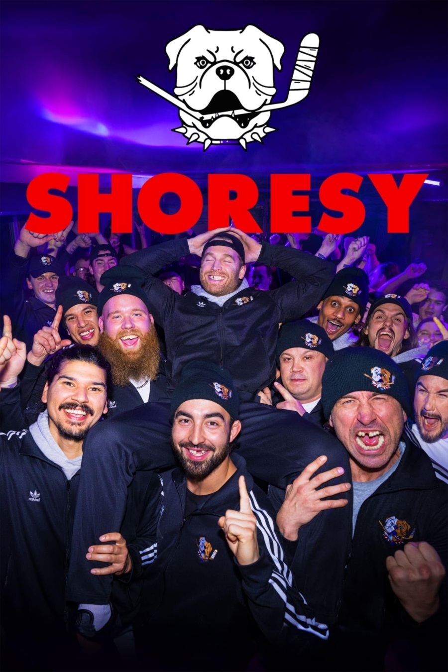 Promotional poster for Shoresy, the Canadian ice hockey show. The whole team of degens and sluts are in dark-blue Adidas trackies on a party bus, yelling and screaming at the camera, celebrating their win. Maximum missing teeth are visible. Shoresy is on the shoulders of his team mates, leaning back, eyes closed grinning, showing off his chirping mouth and missing teeth.